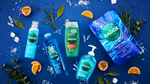 Five Radox products shown on a blue background with herbs, fruit, and salt scattered around