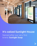Modern office lobby with Sunlight House signage and two people walking past large windows.